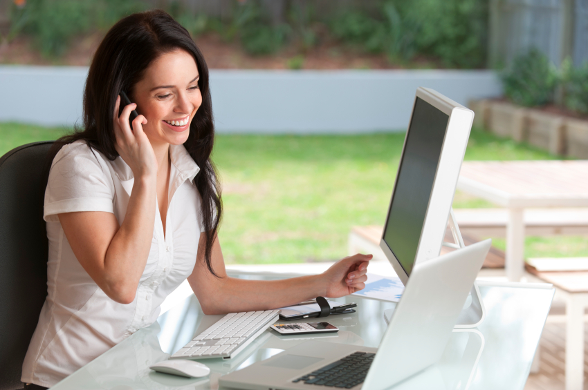 Beautiful young woman is talking on mobile phone in office